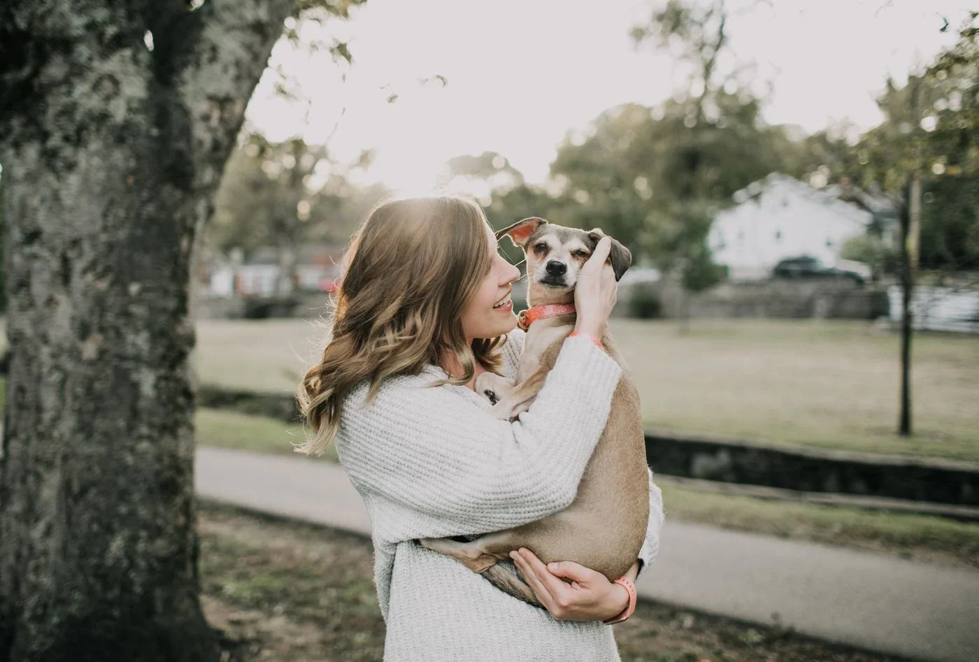 A person holding their dog close in a park